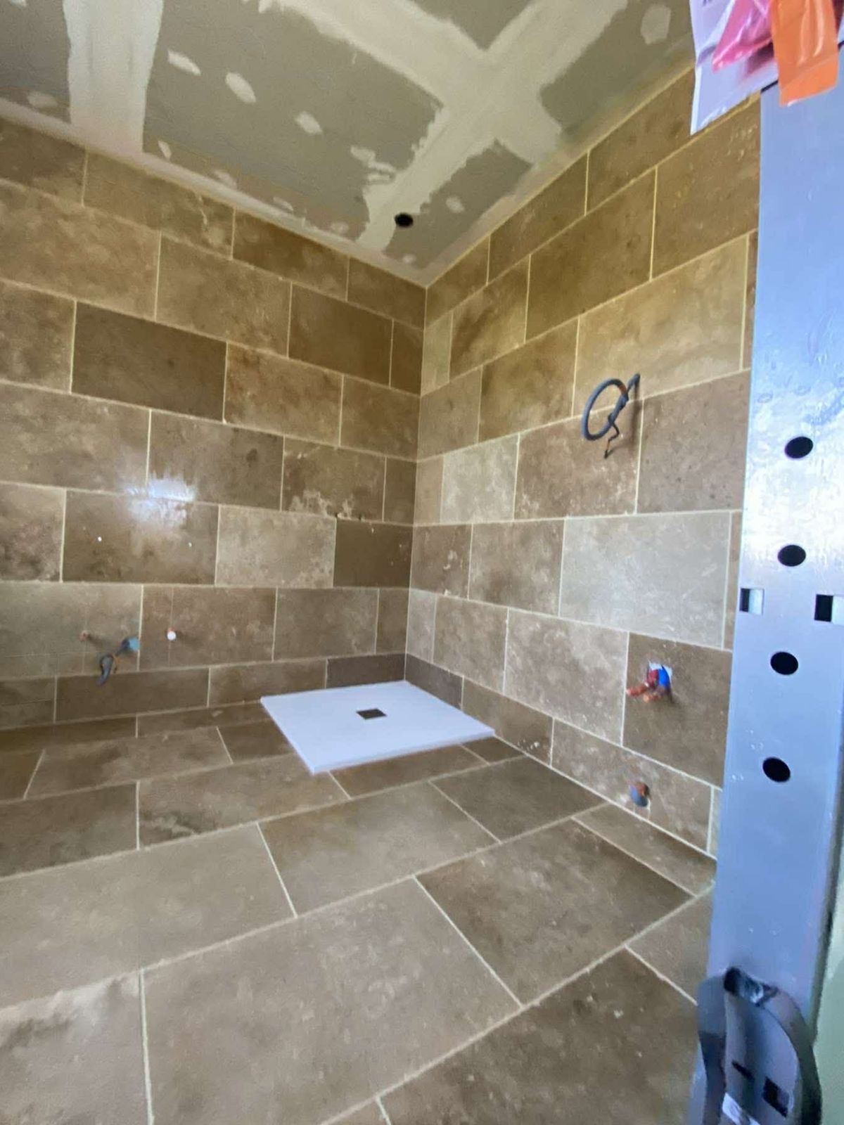 Salle d’eau en cours de carrelage, faïence beige au mur
